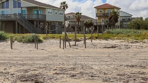 Une propriété située en bord de mer, avec des maisons à plusieurs étages, des passerelles en bois et une plage de sable.