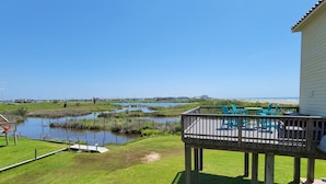 Une terrasse avec des sièges extérieurs donnant sur un plan d’eau et un paysage lointain.
