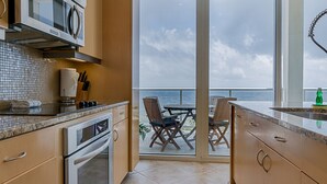 A modern kitchen with a view of the ocean through large sliding glass doors. - Seas the Day in This Luxury Condo at Diamond Beach Ocean Views Incredible Pools Amenities (Galveston)
