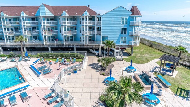 Hotel à beira-mar com várias varandas, piscina e áreas de estar ao ar livre.