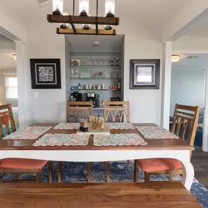 A dining area with a long wooden table, four chairs, and a chandelier.