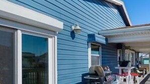 A blue house with a covered porch, a sliding glass door, and outdoor furniture. - Walk to the Beach Ocean Views Yard Game Room (Galveston)