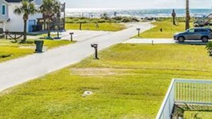 A beachfront property with a house, a pathway, and a parked car. - Walk to the Beach Ocean Views Yard Game Room (Galveston)
