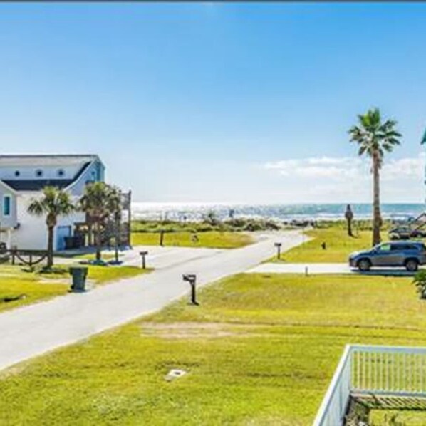 A beachfront property with a house, a pathway, and a parked car.