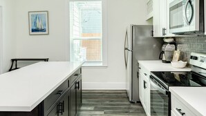 A modern kitchen with white cabinetry, stainless steel appliances, and a large window. - Adventure Awaits Close to the Beach (Galveston)