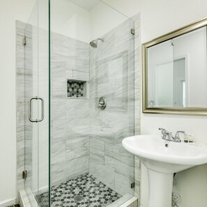 A bathroom with a glass-enclosed shower, a sink, and a mirror.