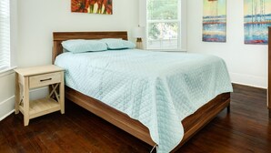 A bedroom with a wooden bed, a nightstand, and two paintings on the wall. - Adventure Awaits Close to the Beach (Galveston)