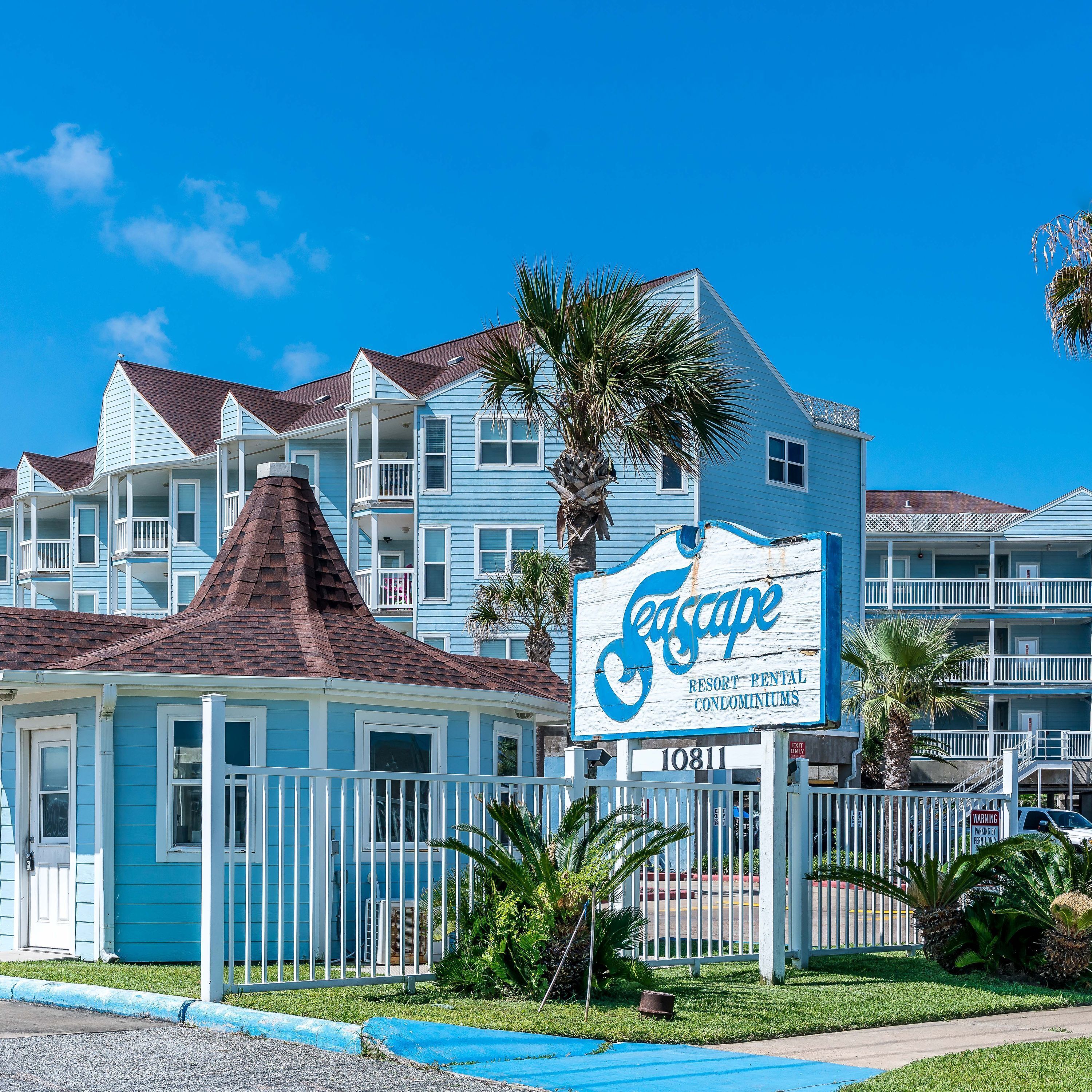A resort rental condominium complex with a prominent sign, multiple balconies, and a well-maintained lawn.