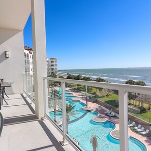 A balcony with a view of a swimming pool and ocean. - Western Waves Dreamy Diamond Beach Condo - Mind-blowing Views Amenities (Galveston)