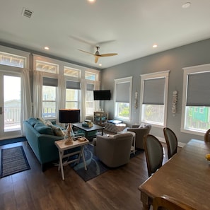 A spacious living room with a sofa, chairs, a coffee table, and a dining table. - Beachside Paradise Retreat With Luxury (Galveston)