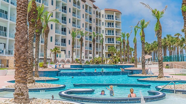 A resort with multiple swimming pools, palm trees, and a multi-story building with balconies. - Welcome to Your Ultimate Getaway (Galveston)