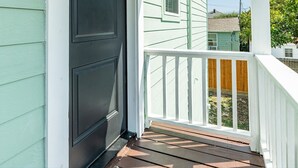 A porch with a dark door, white railings, and a view of neighboring houses. - Have fun Relax and Stay Close to the Beach (Galveston)