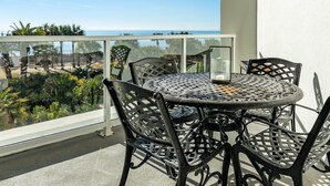 A round metal table with chairs on a balcony with a view of the ocean. - Warm and Welcoming Views at Diamond Beach (Galveston)