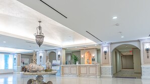 A spacious lobby with a reception desk, a chandelier, and a decorative fountain. - Warm and Welcoming Views at Diamond Beach (Galveston)