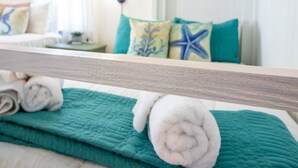 A neatly made bed with teal bedding and rolled white towels. - In-home Bar Lounge and Arcade Stay Entertained at The Sea Shed (Galveston)