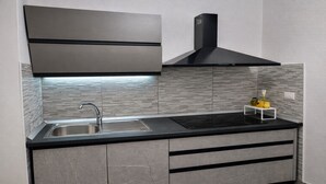 Una cocina moderna con un lavamanos de acero inoxidable, encimera negra y armarios grises.