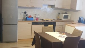 A kitchen with a dining table and chairs, a refrigerator, cabinets, and a microwave.
