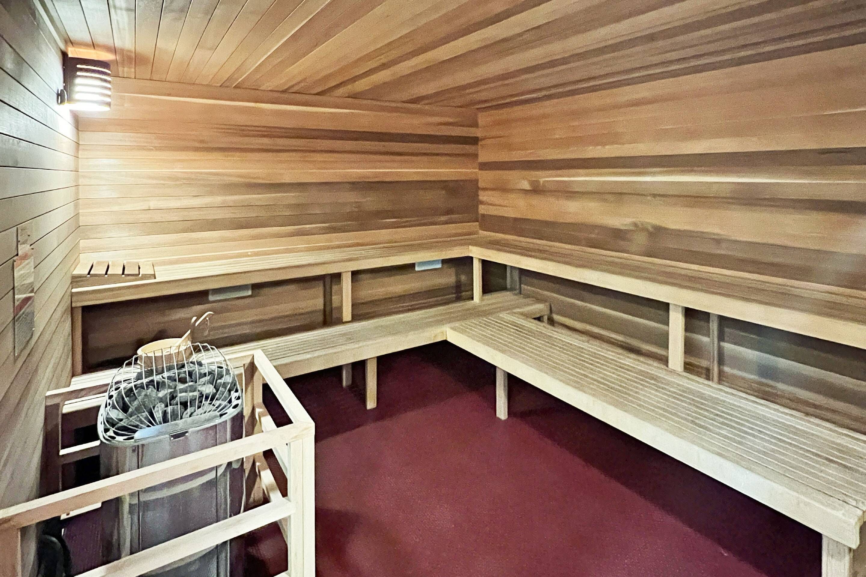 A sauna with wooden benches and a metal basket.