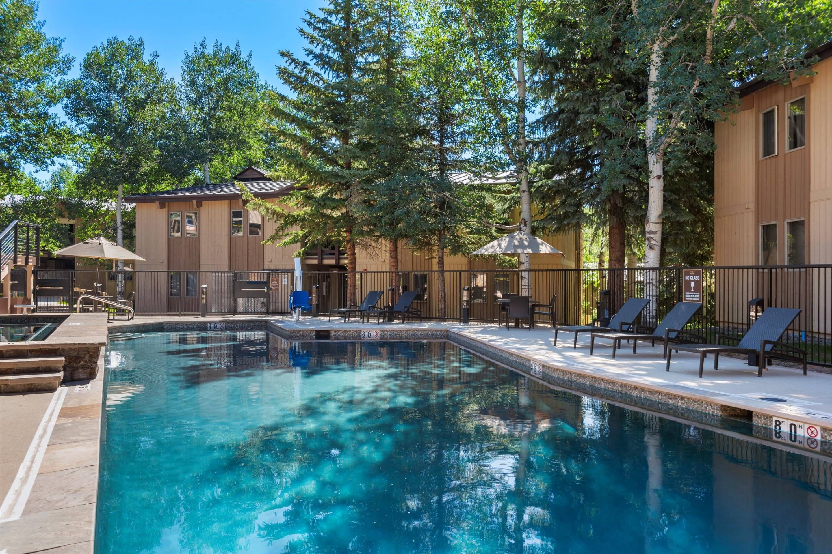 Une piscine avec des chaises longues et un bâtiment en bois en arrière-plan.