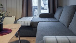 A modern living room with a grey sofa, a wooden coffee table, and a window with curtains.