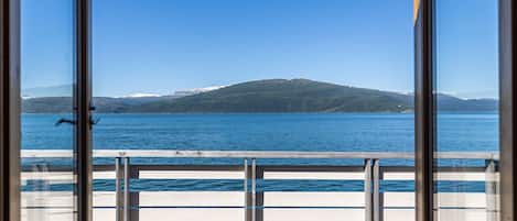 A view from a room with large windows overlooking a calm lake and a distant mountain range.
