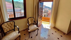 A room with two upholstered chairs, a large window with a view of a balcony, and a door leading to an outdoor area. - Alma Hostel (Vilaflor)