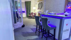 Eine Cocktailbar mit Barhocker, einer Neonreklame und einem herzförmigen Spiegel an der Wand.