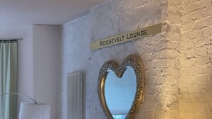 A cozy lounge area with a fireplace, two armchairs, a table, and a heart-shaped mirror on the wall. - The Chatwal Boutique Hotel (Blackpool)