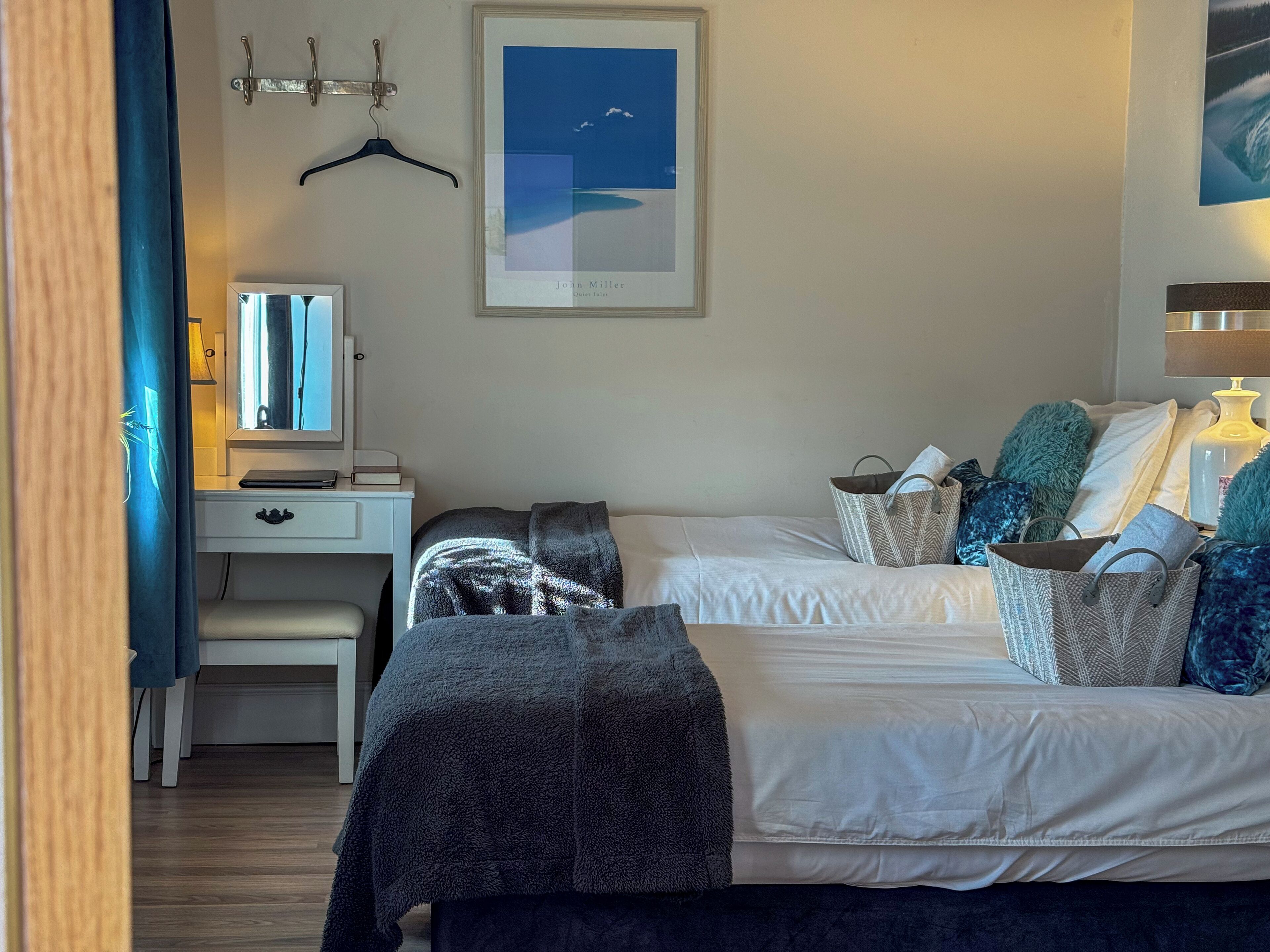 A bedroom with a bed, bedside table, dresser, and a framed picture on the wall.