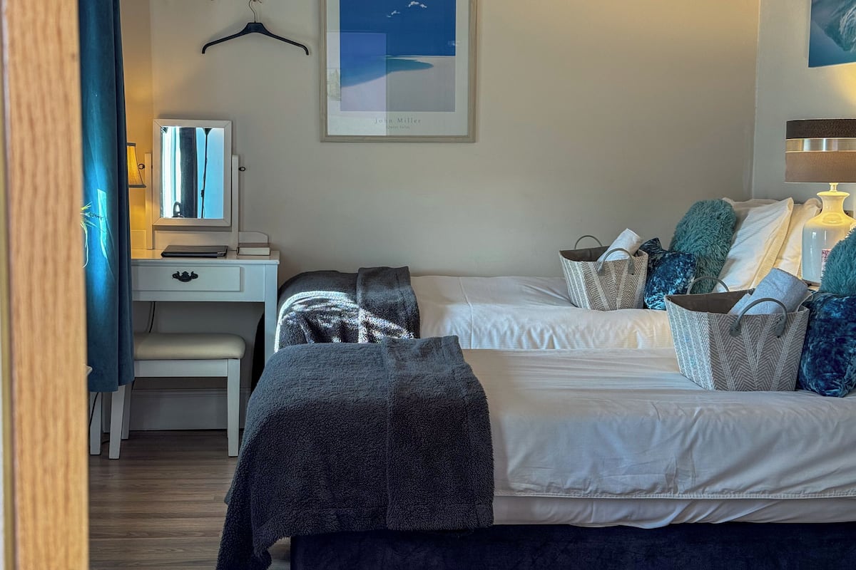 A bedroom with a bed, bedside table, dresser, and a framed picture on the wall.