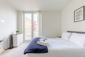 A hotel room with a bed, a bedside table, a radiator, and a window with a view of buildings. - Radiant 1BDR Retreat with WiFi in North Maida Vale (London)