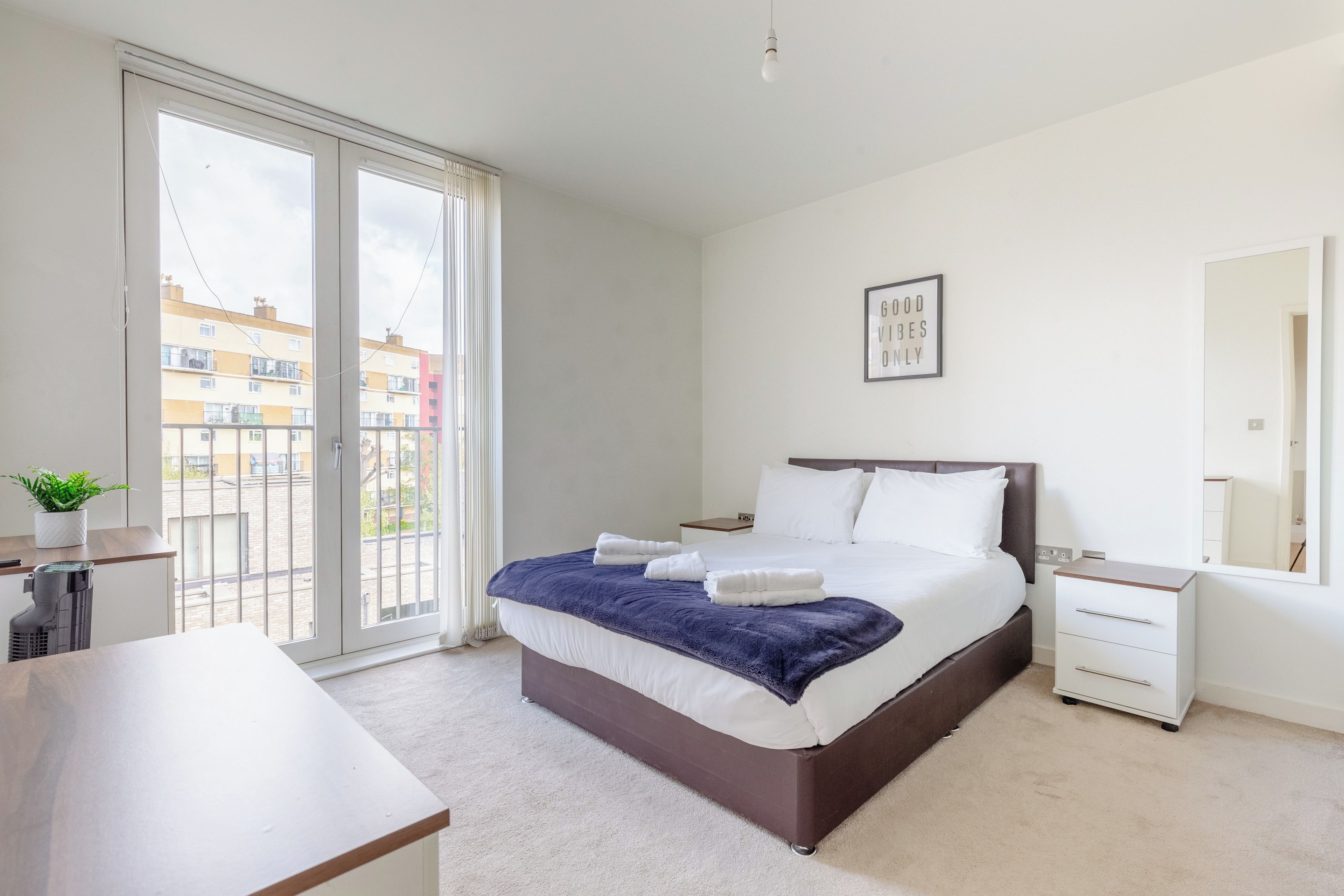 Une chambre d’hôtel avec un lit, une table de chevet, un miroir et une vue sur l’extérieur.
