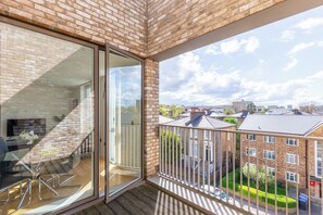 A balcony with a glass door leading to a room with a chair and a table.