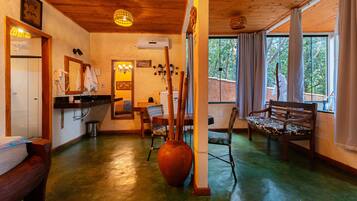 A room with a wooden ceiling, a large vase, a wooden bench, and a window with curtains.