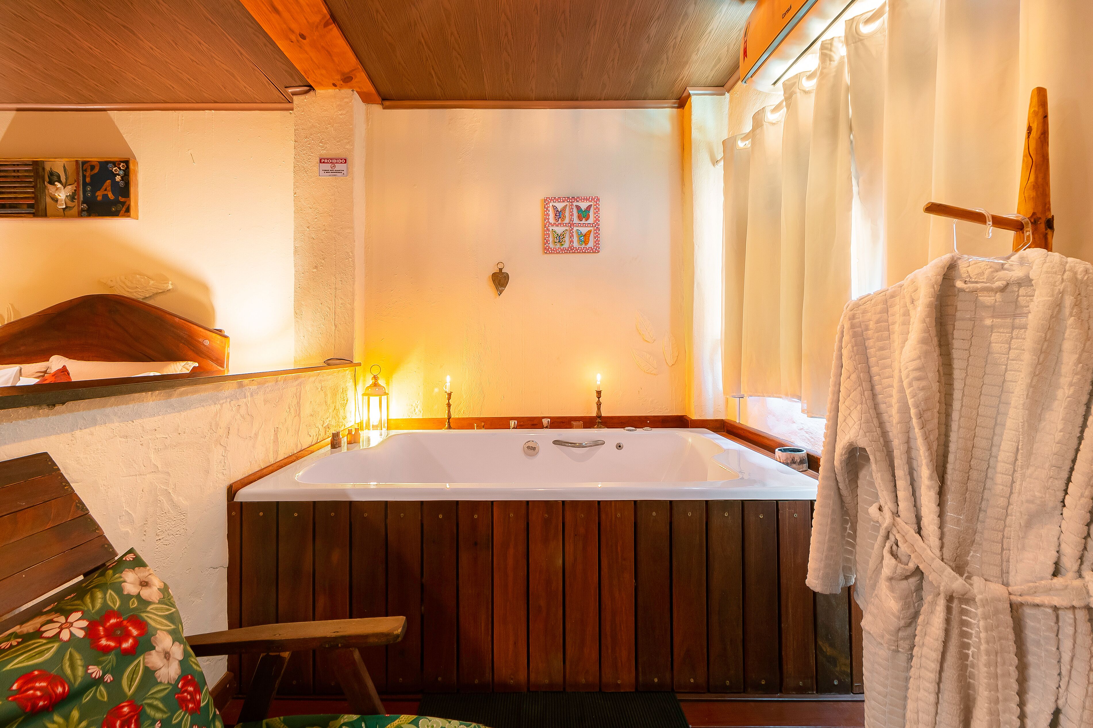 Une salle de bain avec une baignoire en bois, un banc et un peignoir suspendu à un porte-vêtements.