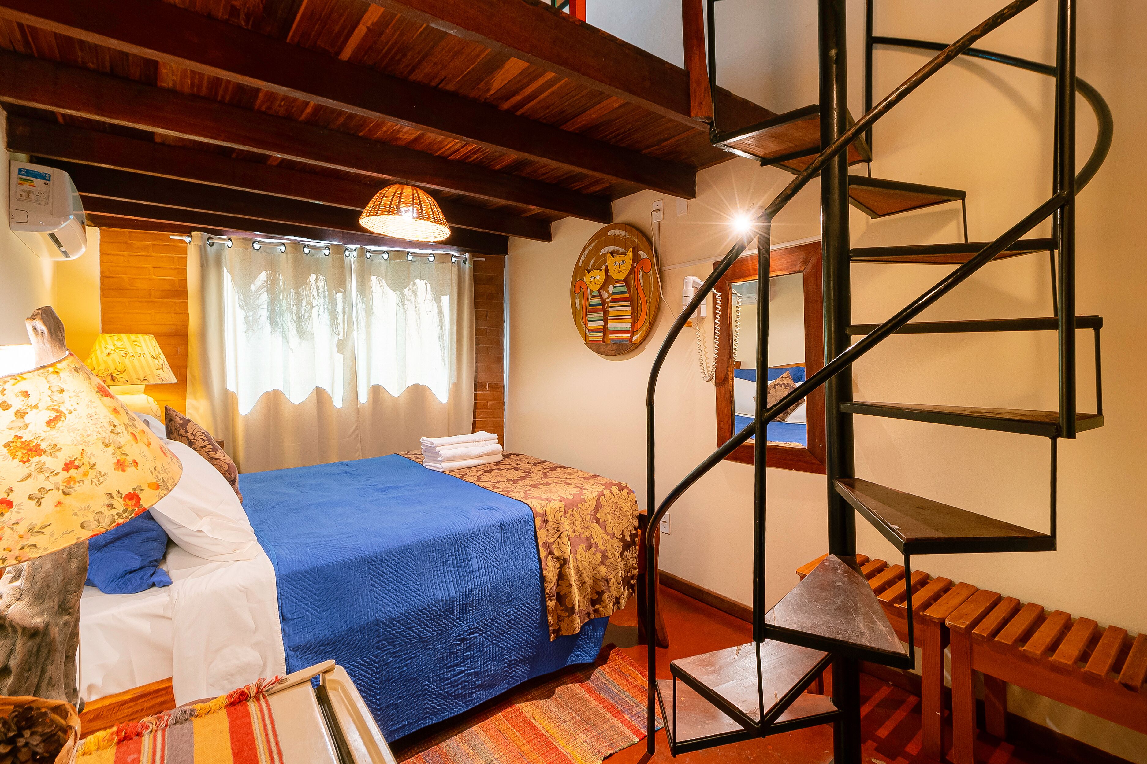 Une chambre à coucher comprenant un lit, un banc en bois, un escalier en colimaçon et une décoration murale.