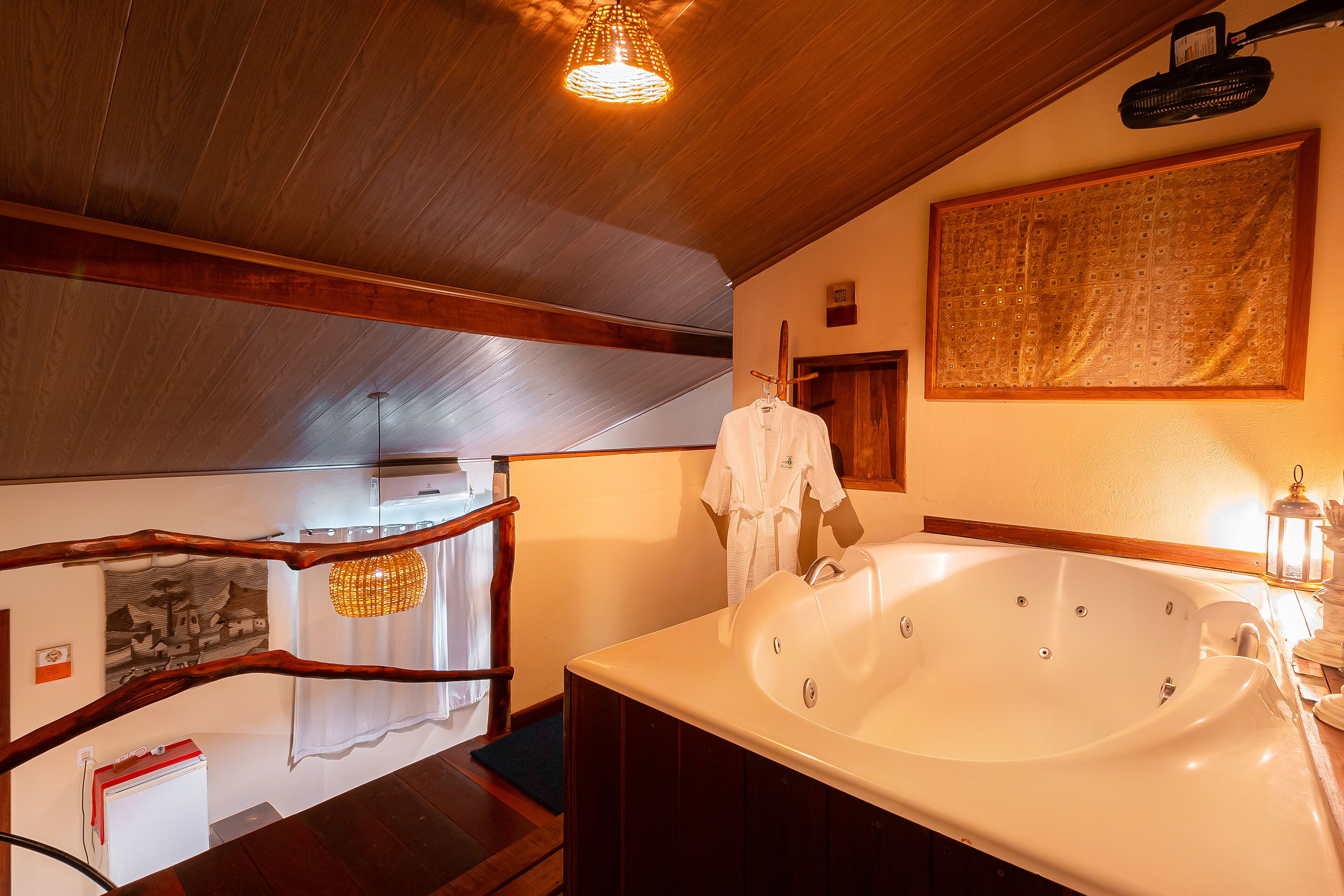 A bathroom with a large bathtub, wooden ceiling beams, a hanging light fixture, and a towel rack.