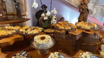 A buffet table with various food items, including pastries, bread, and cheese, arranged on wooden stands and glass dishes.