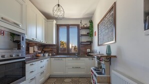 Une cuisine compacte avec des meubles blancs, un four encastré, un évier et une fenêtre donnant sur un beau paysage.