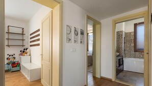 Un couloir avec un banc blanc, une décoration représentant un panda et une voiture jouet pour enfant.