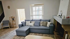 A modern living room with a grey sectional sofa, a wooden coffee table, a wooden ladder shelf, and a staircase leading to an upper level. - Apartment - shaded terrace (Marsanne)