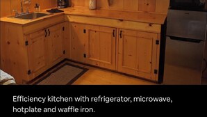 Una cocina compacta equipada con refrigerador, microondas, placa de cocción y plancha para waffles.
