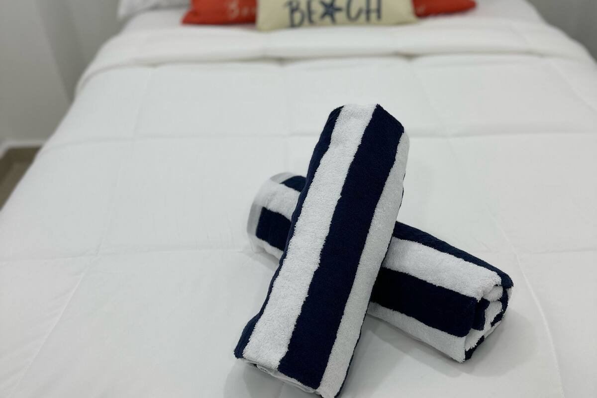 A neatly made bed with white bedding and a pillow with a message.