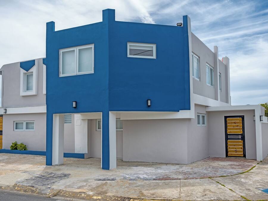 A modern two-story building with a blue and white color scheme, featuring a gated entrance and multiple windows.