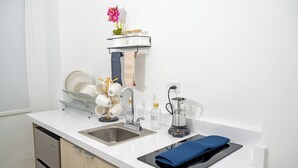 Uma cozinha moderna com bancada branca, pia de aço inoxidável e forno embutido.
