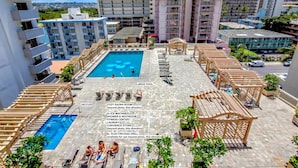 A rooftop pool area with a large pool, jaccuzi, and a cozy sauna room.