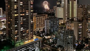 A high-rise building with multiple floors, a parking garage below, and a view of the cityscape at night.