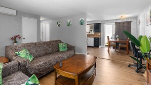 Una sala de estar con un sofá estampado, una mesa de centro y un comedor con mesa y sillas.