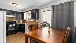 Una cocina moderna con armarios oscuros, una mesa de comedor de madera y un horno empotrado.