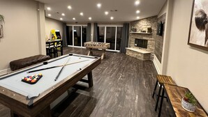 A pool table with pool cues and balls, a foosball table, and a fireplace. - The Escape -family Friendly Close to Fiesta Texas (San Antonio)